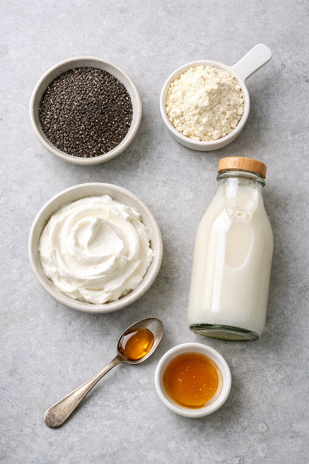 Portrait/Pinterest format () flat-lay overhead shot of all protein chia pudding ingredients arranged artfully on a light