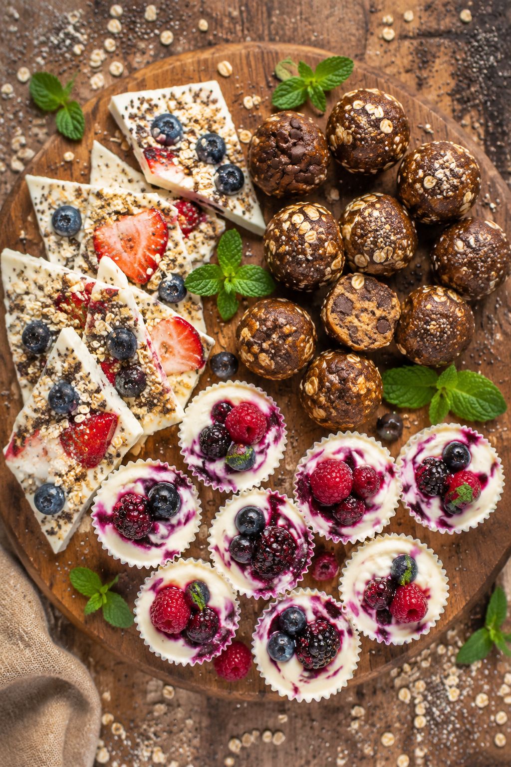 Portrait/Pinterest format () overhead flat lay of assorted protein-packed breakfast bites on a rustic wooden board — Greek